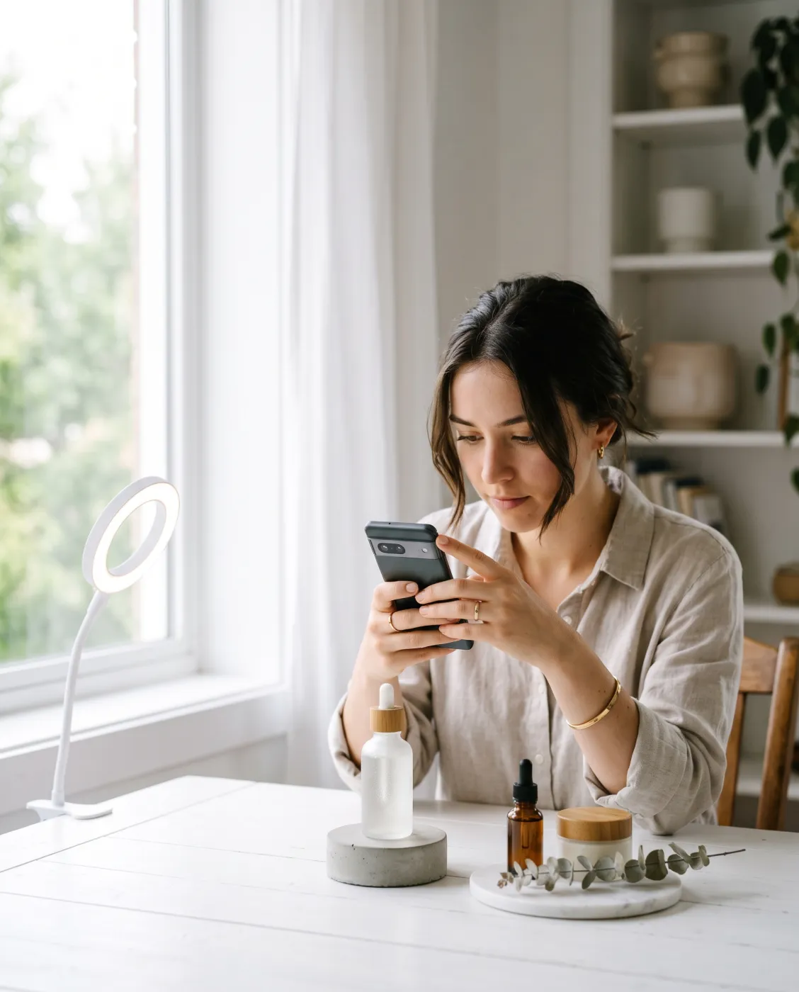 A woman photographing a serum bottle with her phone by a window
